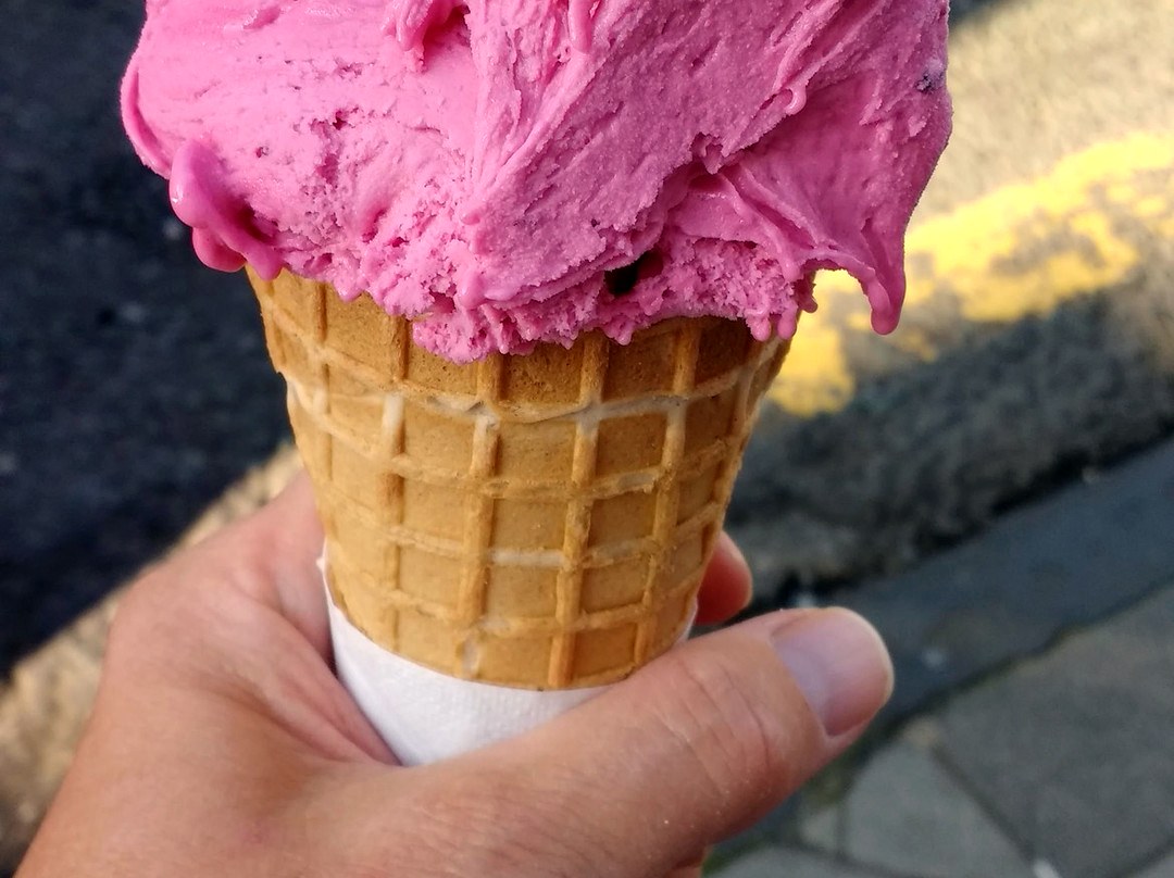 A vibrant cherry gelato cone in a waffle cone